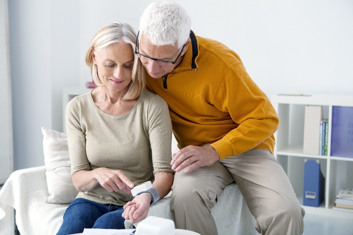 Man and woman sat down looking at remote healthcare monitoring device