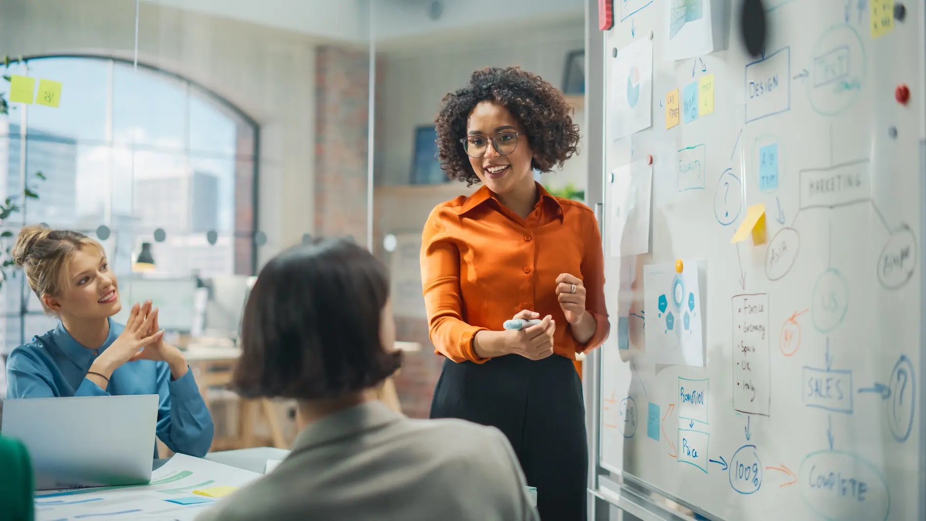 Lady at whiteboard brainstorming IoT project