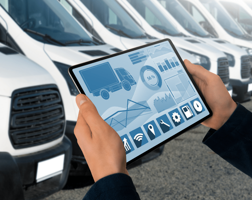 A person holds a tablet with fleet management software displayed, showing charts, maps, and vehicle icons, in front of a row of white commercial vans parked in a lot.