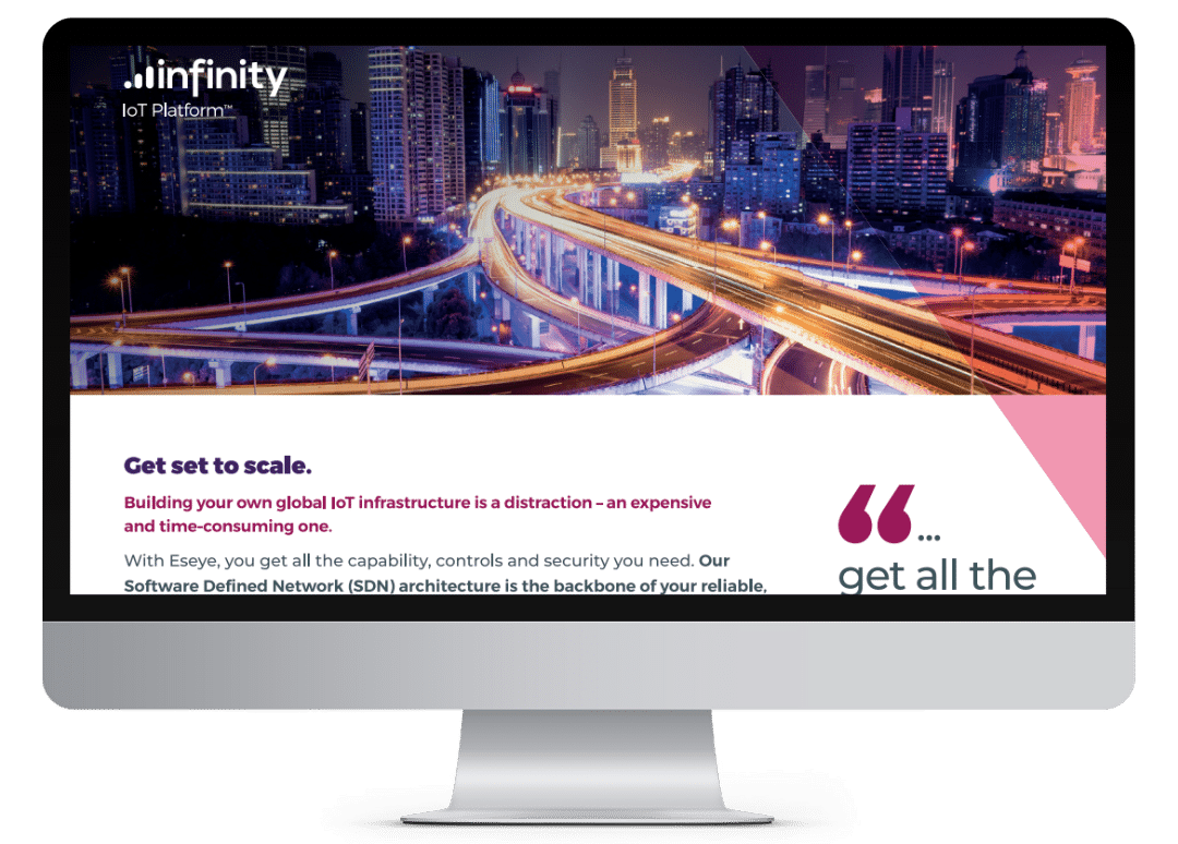 A computer monitor displays a webpage for Infinity IoT Platform, featuring a cityscape with illuminated highways at dusk and text discussing global IoT infrastructure and network architecture solutions.