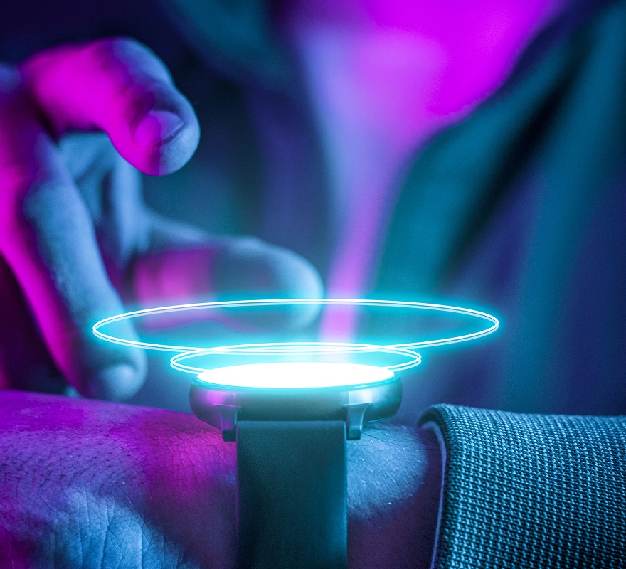 A person’s hand interacts with a smartwatch emitting glowing blue holographic rings, set against a purple and blue background, suggesting advanced or futuristic technology.
